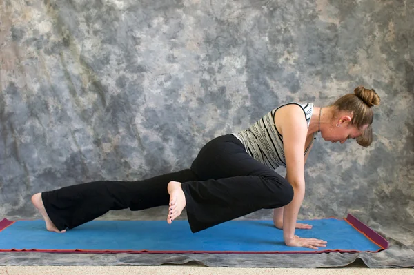 Woman doing Yoga posture high plank knee to elbow variation