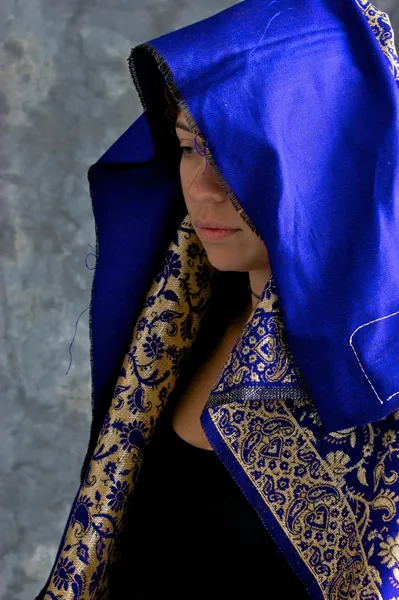 Mystical woman in blue and gold cape with hood