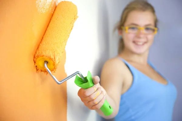 Happy young woman painting wall / focus on the roller — Stock Photo #5435366