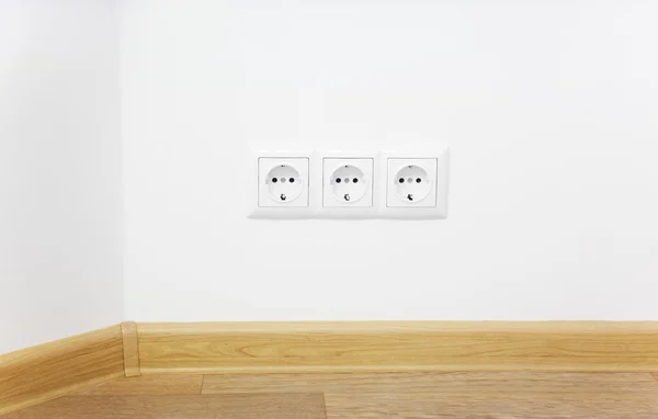 Empty interior white wall with power outlet / wooden floor