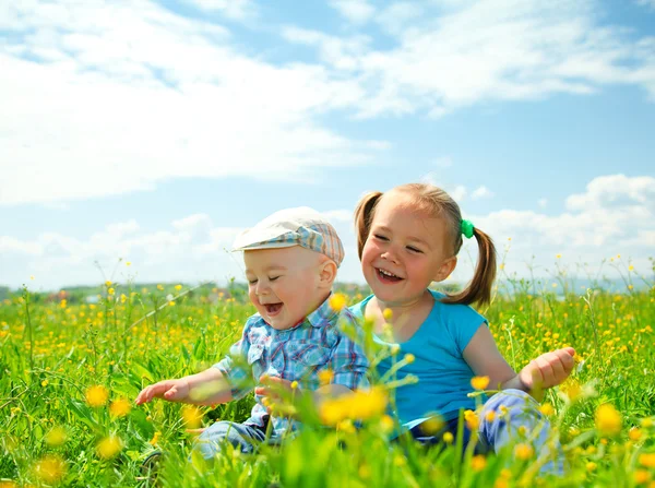 Two children are having fun on green meadow