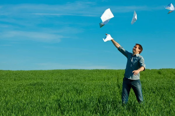 Stock Photo: Young mthrowing paper in green field
