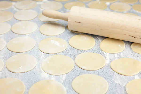 Round shape of the dough and rolling pin with flour on the table