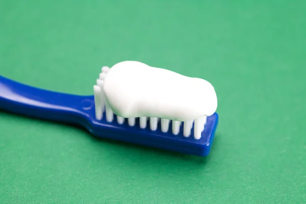 Blue toothbrush and tooth paste on a green background