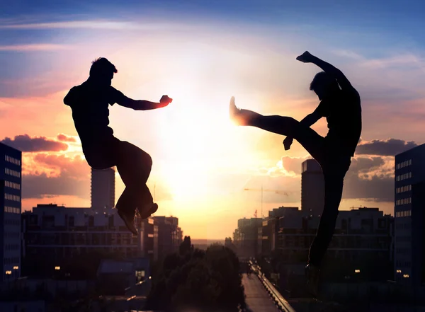 Two capoeira fighters over city background