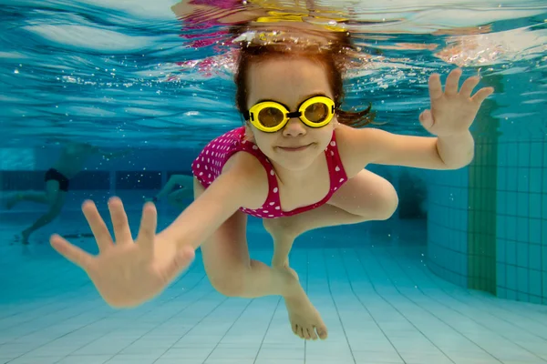 The girl smiles, swimming under water in the pool — Foto Stock #5588990