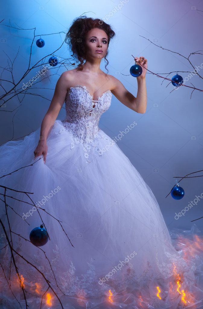 Bride in a wedding dress walking between winter trees decorated with 