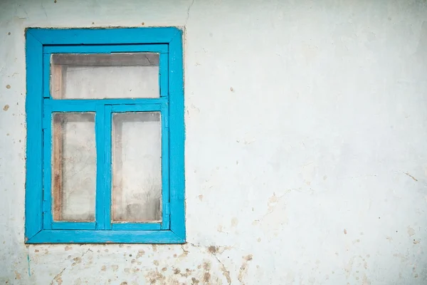 Old cracked wall with window painted with blue