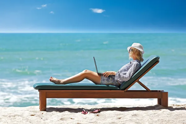 Young woman with laptop on the tropical beach