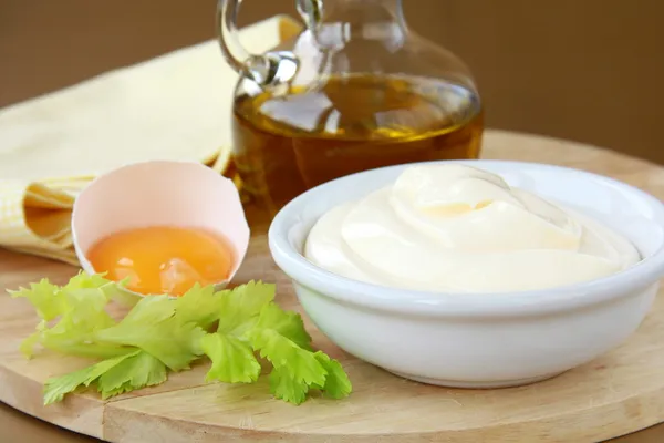Mayonnaise with egg and olive oil on a wooden board
