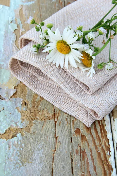 Bouquet of daisies on the linen bag on a wooden table rustic still life