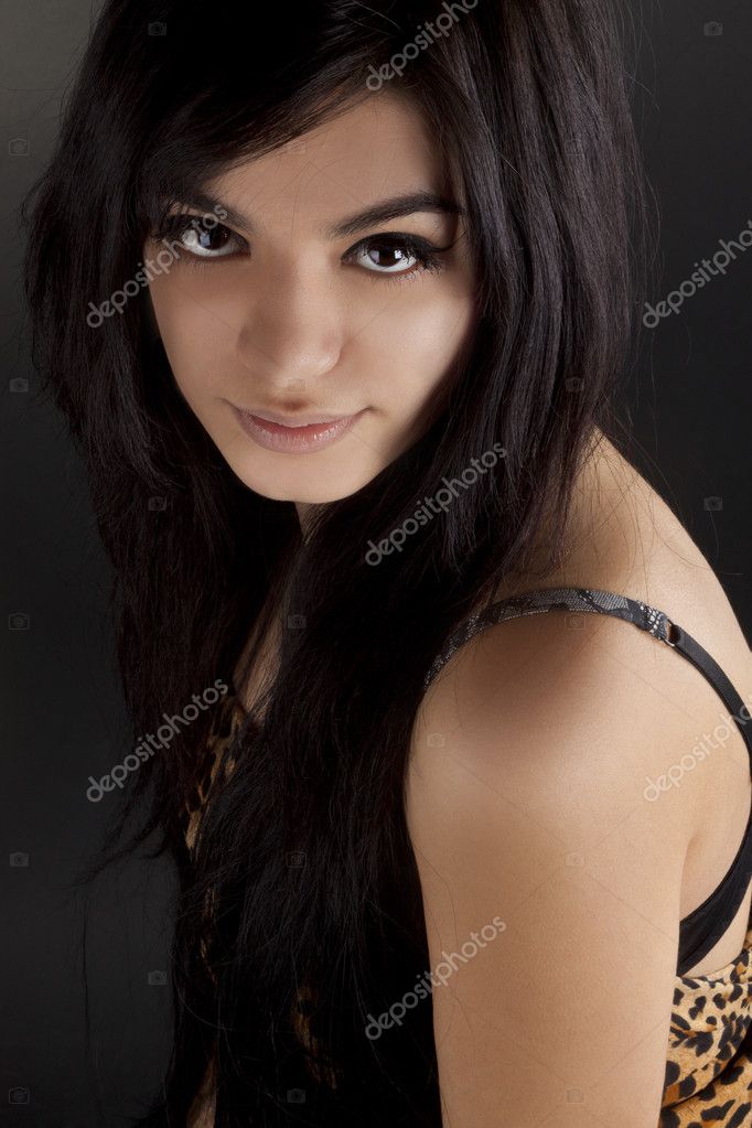 Portrait of a beautiful darkhaired tanned girl on a black background