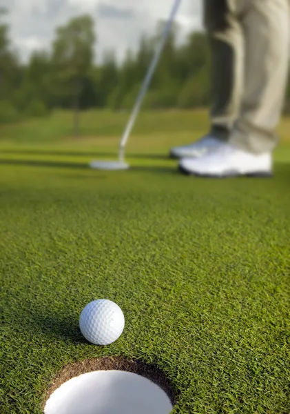Golfer putting, selective focus on golf ball