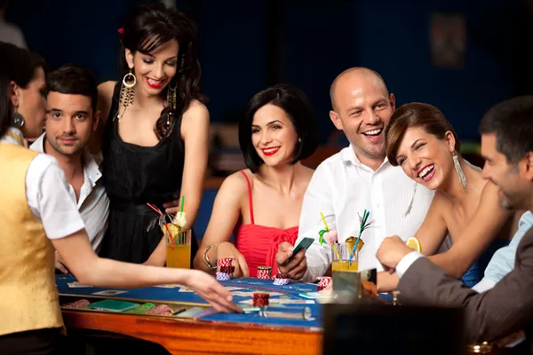 Laughing friends playing cards in a casino