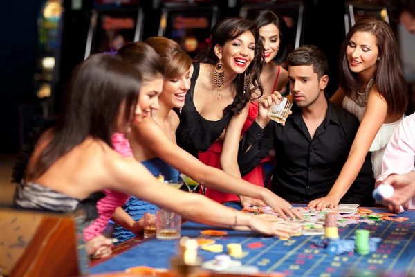 Happy caucasian friends playing roulette in casino