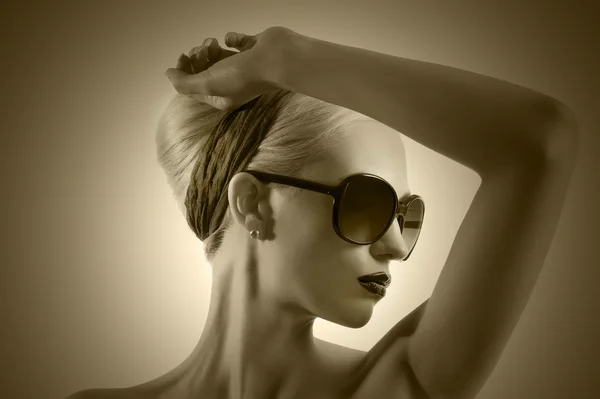 Fashion shot of blond girl with sunglasses posing against white