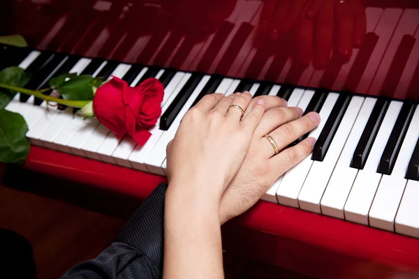 Hands of married couple on piano