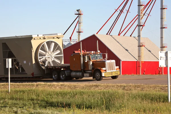 Truck hauling grain drying bin in scenic Saskatchewan