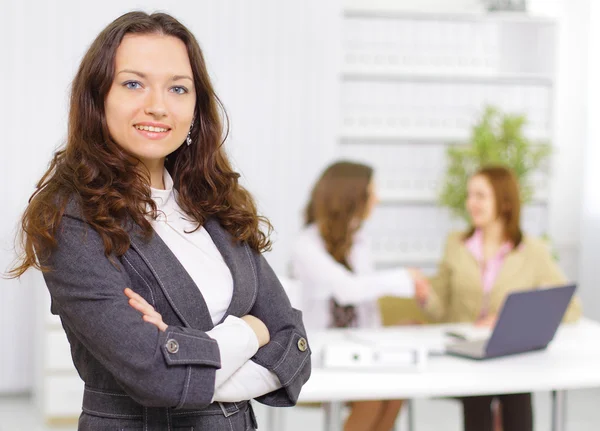 Successful business woman standing with her staff in background at office