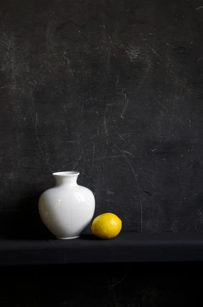 White vase and lemon on black background