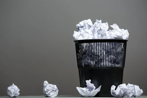 Recycle bin filled with crumpled papers
