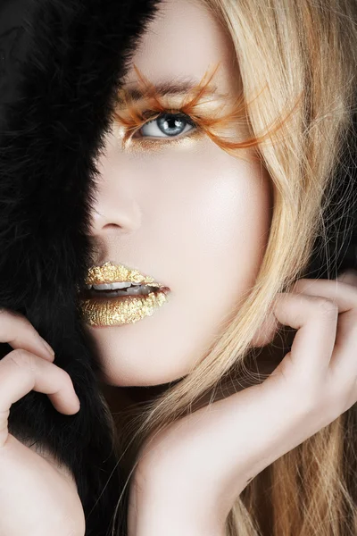 Gold leaf and false eyelashes on a blond woman.