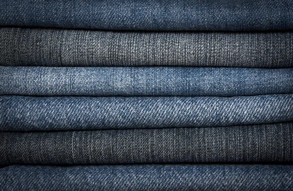 A pile of different types of blue denim jeans closeup