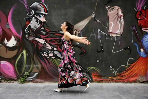 Elegant fashion woman running over urban graffiti