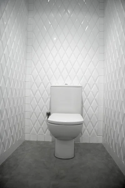 Toilet in a white room diamond shape tiles