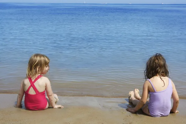 Tow sisters sit on beach bathing suit swimsuit