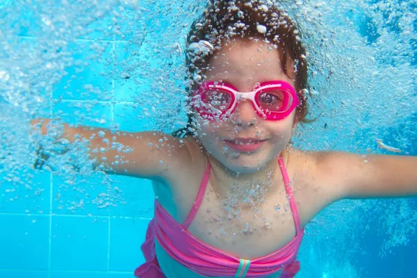 Underwater little girl pink bikini blue swimming pool
