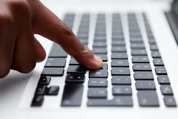Black finger typing on computer keyboard