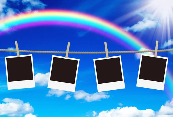 Blank photo frames hanging against rainbow sky