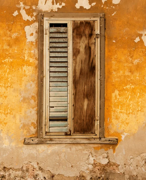 Grunge window with blinds and shutter over old orange wall