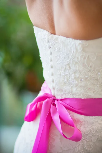 Pink ribbon on bride\'s dress
