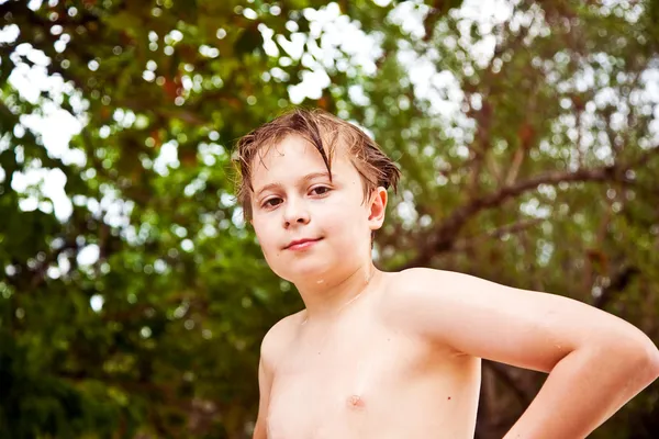 Young boy with wet hair comes out of the sea smiling and looks