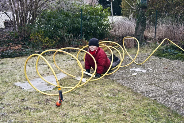 Boy playing with frozen hose pipe