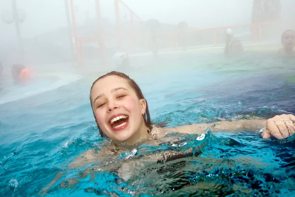 Girl has fun in the outdoor thermal pool in wintertime