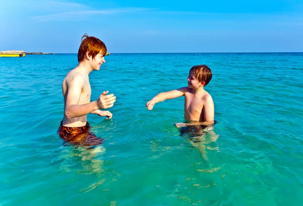 Brothers are enjoying the clear warm water at the beautiful beach