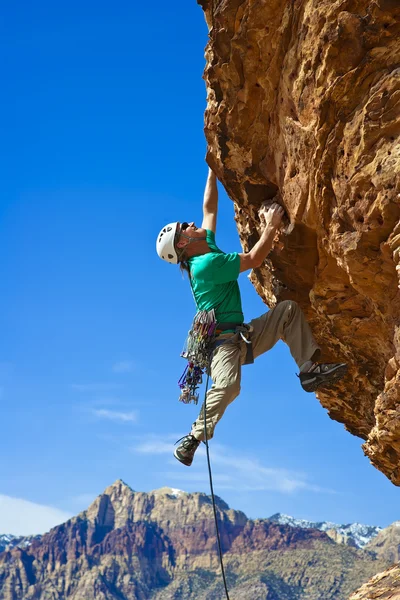 Male rock climber reaching for the summit.