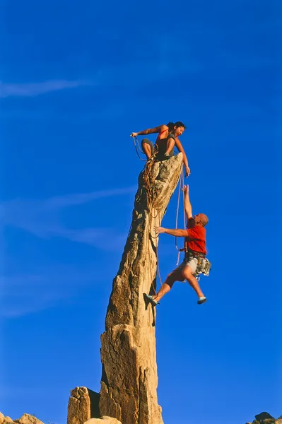 Rock climbing team reaching the summit.
