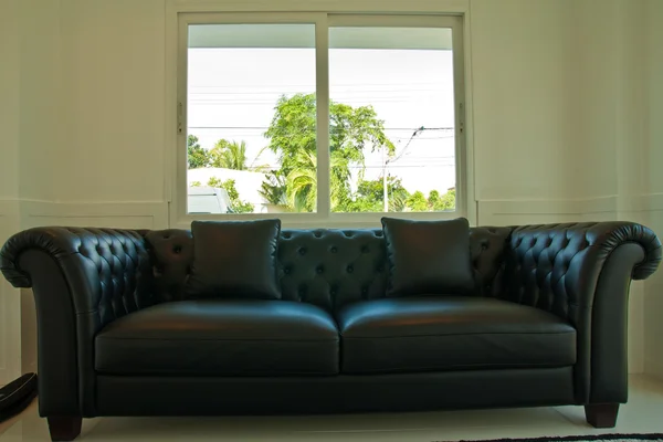 Black leather couch in front of windows