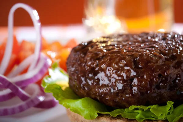 Beef burger with onion and beer on background