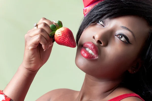 Beautiful young black woman eating a strawberry