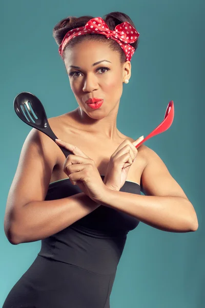 Beautiful happy pin-up style housewife with kitchen utensils