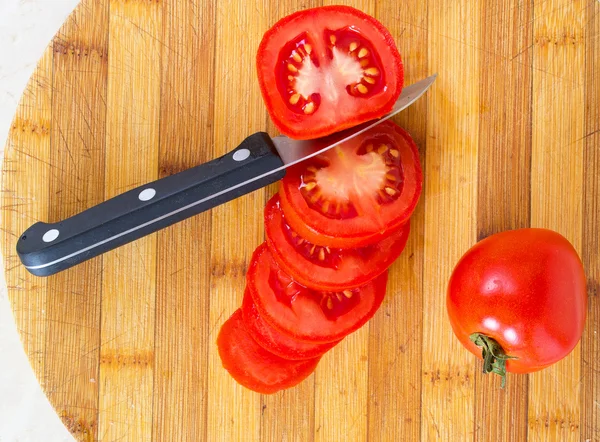 Sliced ​​tomatoes with a knife on a board