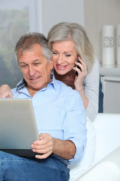 Senior couple at home surfing on internet