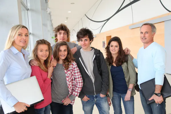Portrait of teenagers and teachers standing on school hall