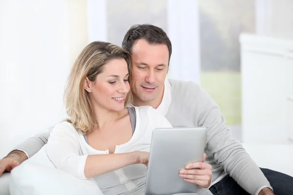 Couple sitting in sofa with electronic tab