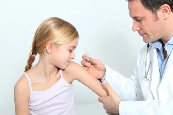 Doctor doing vaccine injection to blond little girl